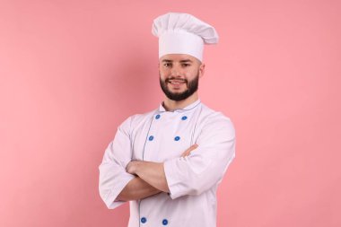 Pembe arka planda çapraz kollu, üniformalı şekerlemecinin portresi.