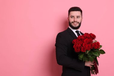 Pembe arka planda kırmızı gül buketi olan mutlu adam, mesaj için yer.