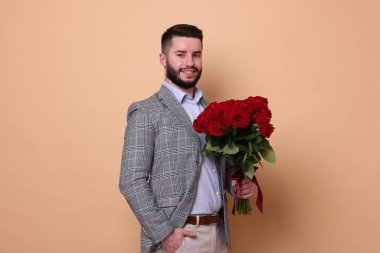 Bej arka planda kırmızı gül buketi olan mutlu adam.