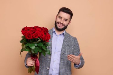 Bej arka planda kırmızı gül buketi olan mutlu adam.