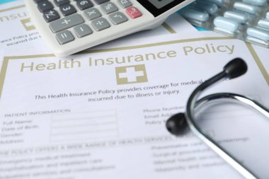 Sağlık sigortası, steteskop, hesap makinesi ve haplar, yakın plan.