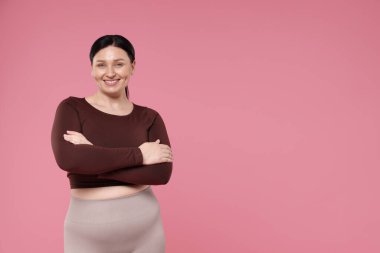 Artı beden ölçülerinde kadın, pembe arka planda, mesaj için yer var.
