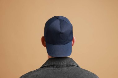 Beyzbol şapkalı, bej arka planda bir adam. Tasarım için model