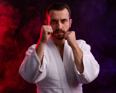 Renkli ışıklar içinde karate dövüşçüsü ve siyah arka planda duman
