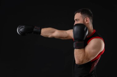 Siyah arka planda dövüşen boks eldivenli adam.