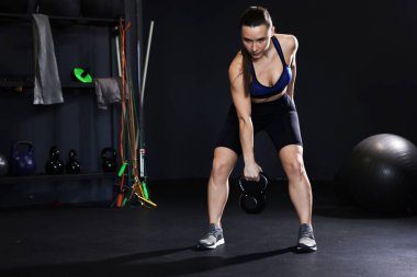 Spor salonunda kettlebell ile antrenman yapan atletik bir kadın. Metin için boşluk
