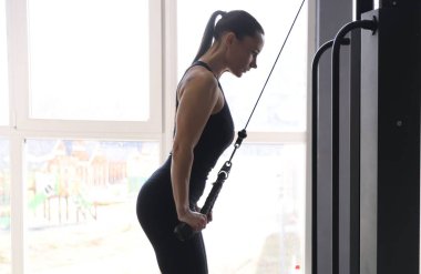 Spor salonunda makara makinesinde çalışan atletik kadın.