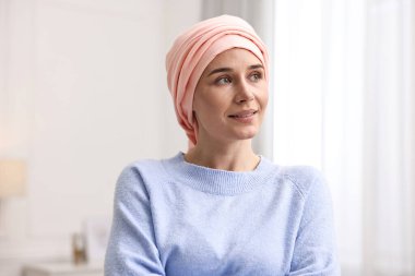 Kapalı alanda türbanlı kanserli gülümseyen kadının portresi.