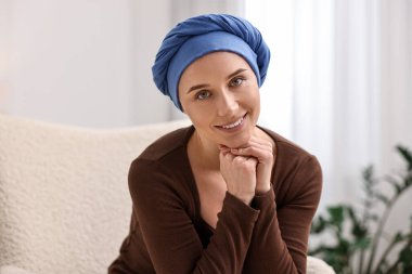 İçerideki koltukta türbanlı kanserli gülümseyen kadının portresi.