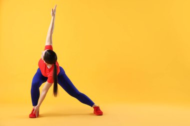 Spor giyimli kadın turuncu arka planda egzersiz yapıyor, metin için boşluk var.