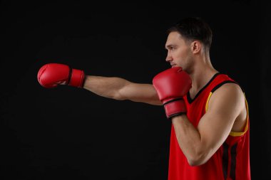 Siyah arka planda dövüşen boks eldivenli adam.