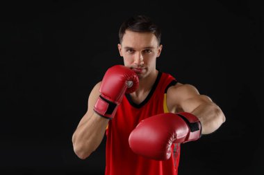 Siyah arka planda dövüşen boks eldivenli adam.