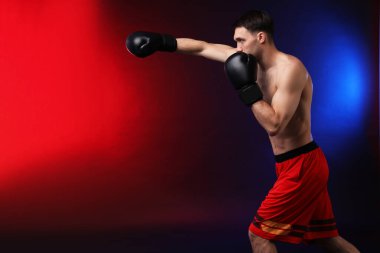 Boks eldivenli adam karanlık arka planda neon ışıklarda dövüşüyor, metin için yer var.