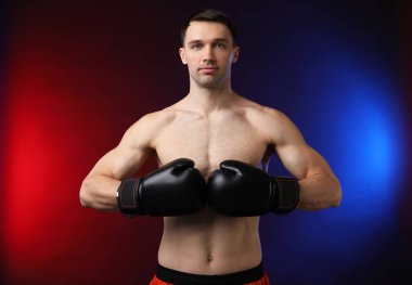 Siyah arka planda, neon ışıklarda boks eldivenli adam.