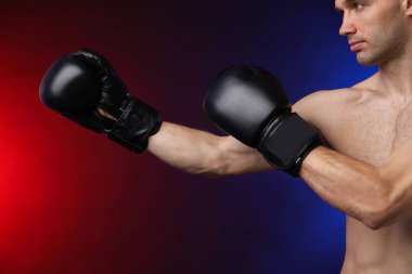 Boks eldivenli adam karanlık arka planda neon ışıklarda dövüşüyor, yakın plan.