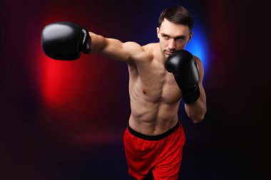 Boks eldivenli bir adam neon ışıklarıyla arka planda savaşıyor.