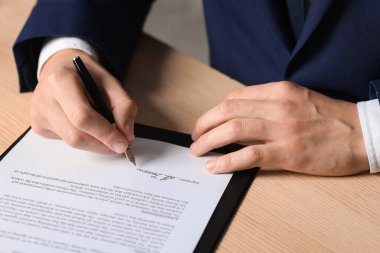 Ahşap masaya imza atan adam, yakın plan