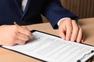 Ahşap masaya imza atan adam, yakın plan