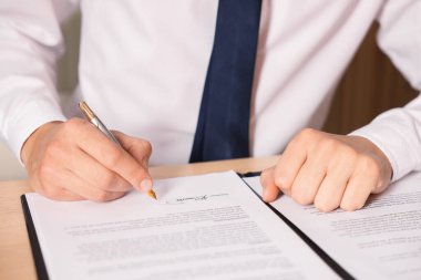 Adam masadaki belgeye imza atıyor, yakın plan