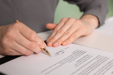 Beyaz masadaki belgeye imza atan kadın, yakın plan