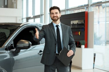 Salonda yeni arabanın yanında el sıkışan mutlu bir satıcı.