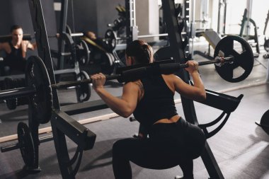 Spor salonunda halterle antreman yapan atletik bir kadın.
