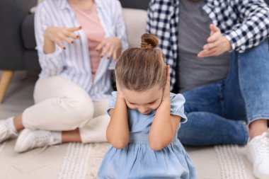 Ailesinin yanında kulaklarını tıkayan gücenmiş küçük bir kız. Aile içi anlaşmazlık