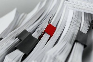 Farklılık, eşsizlik, bireysellik. Siyah cilt klipsli belge yığını ve bir kırmızı, yakın plan