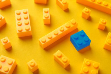 Farklılık, eşsizlik, bireysellik. Renkli arka planda sarı olanlar arasında mavi yapı taşı