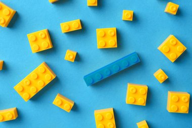 Farklılık, eşsizlik, bireysellik. Renkli arka planda sarı olanlar arasında mavi yapı bloğu, üst görünüm