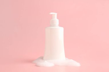 Pembe arka planda köpüklü bir şişe kozmetik ürünü.