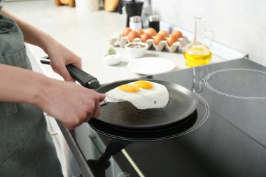 Mutfakta kızartma tavasından yumurta alan kadın, yakın plan.