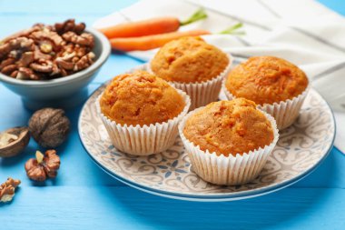 Açık mavi ahşap masada havuçlu kek ve ceviz, yakın plan.