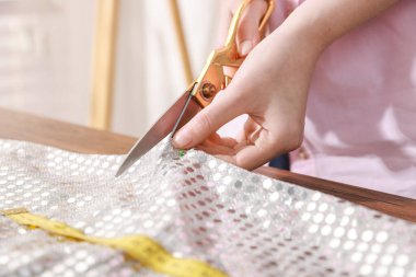 Atölyede kumaşı pullarla kesen kadın, yakın plan.