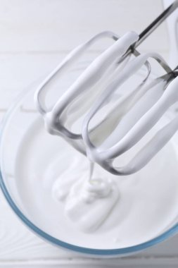 Krem şanti ve el mikserini beyaz ahşap masada, üst manzara.