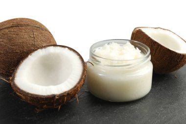 Cam kavanozda organik hindistan cevizi pişirme yağı ve beyaz arka planda siyah masada taze meyveler.