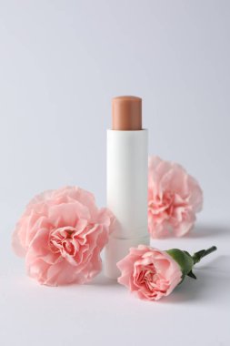 Beyaz arka planda dudak kremi ve Eustoma çiçekleri, yakın plan.