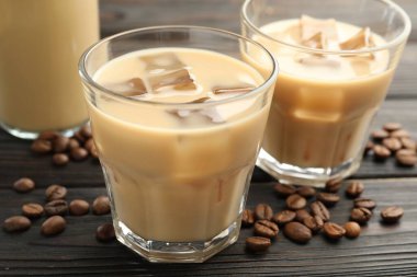 Bardakta kremalı kahve likörü ve ahşap masada fasulye, yakın plan.