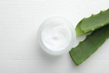 Beyaz ahşap zemin üzerinde krema ve aloe yaprakları, düz yatıyordu