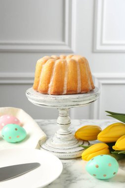 Lezzetli kek, Paskalya yumurtası ve beyaz mermer masada laleler.