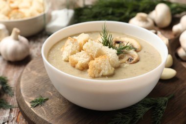 Lezzetli mantar kremalı çorba, kızarmış ekmek, dereotu ve ahşap masa malzemeleri, yakın plan.