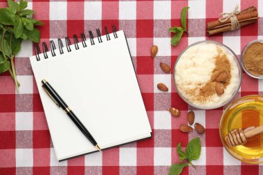 Boş tarif kitabı, tatlı ve malzemeler kırmızı kareli peçete üzerinde, düz uzanmış