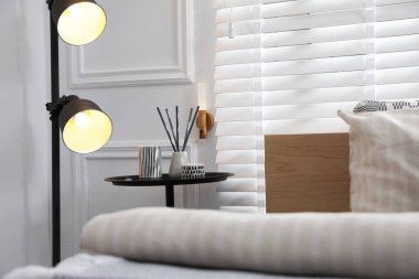 Yatak odasının yanındaki lamba ve sehpa, yakın çekim. İç tasarım