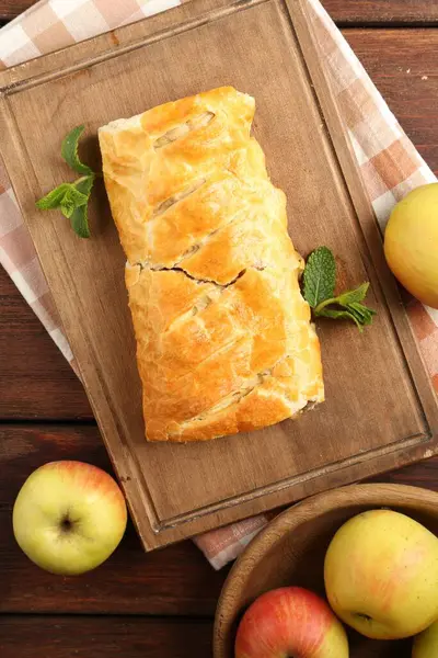Delicious strudel with apples and mint on wooden table, flat lay