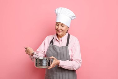 Profesyonel şekerci pembe arka planda krema yapıyor.