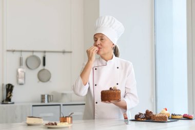 Kıdemli pasta şefi diğer tatlılarla birlikte lezzetli pastayı mutfakta tutuyor.