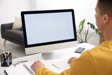 Ofisteki beyaz masada bilgisayarda çalışan bir adam, yakın plan. Tasarım için model