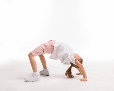 Beyaz arka planda egzersiz yapan tatlı küçük kız.