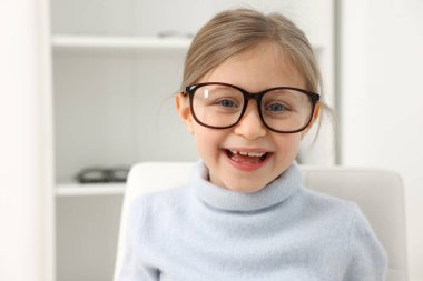 Ofiste gözlük takan küçük bir kız. Mesaj atmak için yer var.