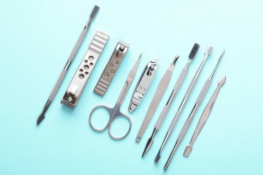 Turkuaz zemin üzerinde farklı manikür araçları kümesi, düz yatar